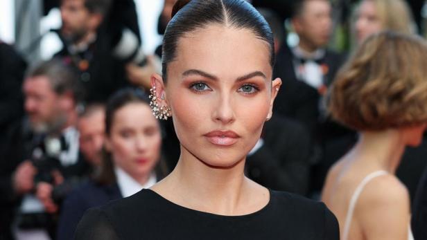 Thylane Blondeau trägt ein elegantes schwarzes Kleid und auffälligen Ohrschmuck auf dem roten Teppich.
