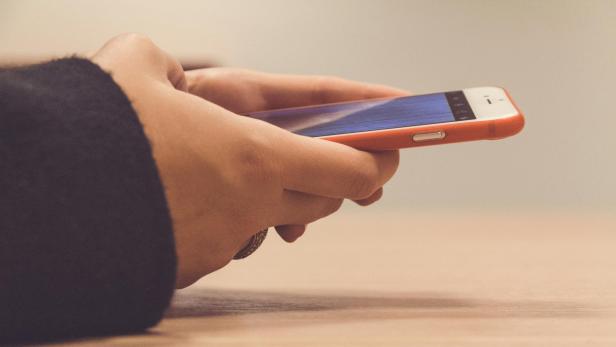 Hände halten ein Smartphone mit geöffnetem Social-Media-Post.