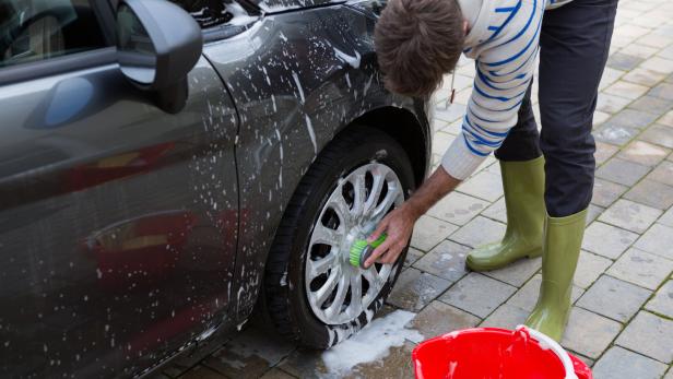 Auto service staff washing a car tyre with sponge