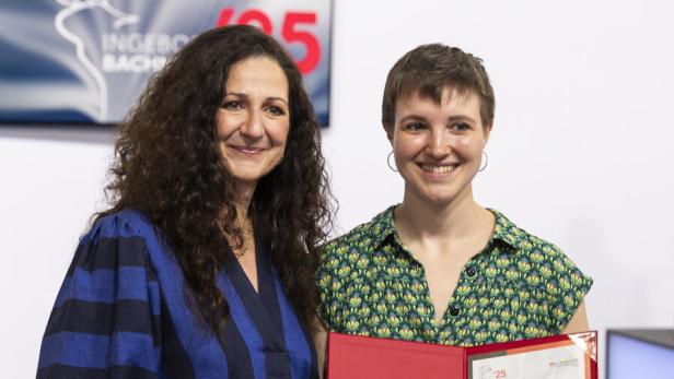 Zwei Frauen lächeln, Naja Kayali steht links, die andere hält eine rote Urkunde offen vor der Brust.