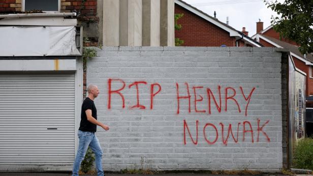 A man walks past a message written on a wall for student Henry Nowak in east Belfast