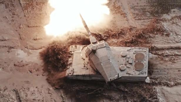 Kampfpanzer mit schlankem Turm feuert eine Kanone ab.
