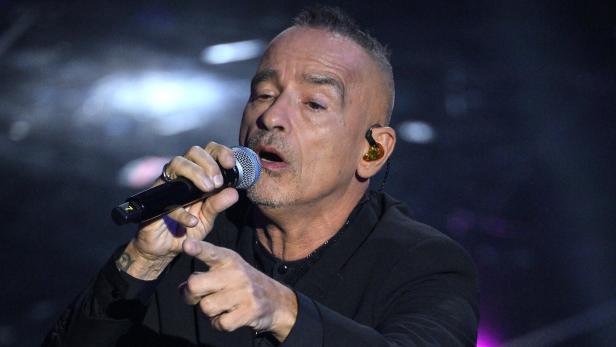 Eros Ramazzotti singt in ein Mikrofon und zeigt mit dem Finger in die Menge.