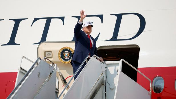 Donald Trump winkt auf der Flugzeugtreppe vor der Präsidentenmaschine.