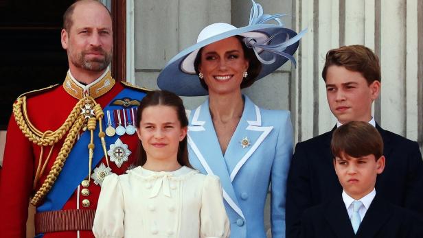 Prinz William, Prinzessin Kate und ihre Kinder George, Charlotte und Louis stehen gemeinsam auf einem Balkon.