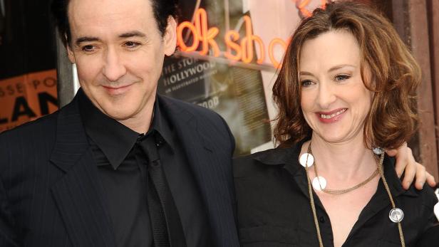 John und Joan Cusack lächeln gemeinsam vor einem Kinoeingang bei einer Veranstaltung.