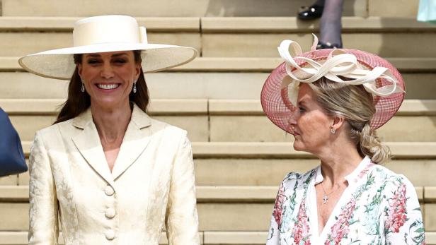 Catherine, Prinzessin von Wales, und Herzogin Sophie stehen in festlicher Kleidung und mit Hüten auf einer Treppe.
