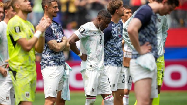 Spieler der österreichischen Fußballnationalmannschaft stehen enttäuscht auf dem Rasen.