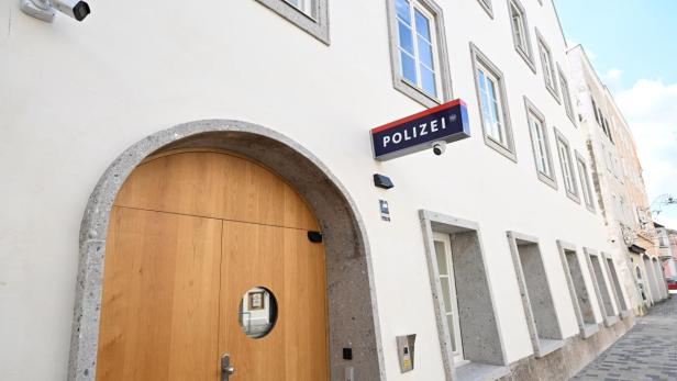 Weiße Polizeistation mit Holzportal und mehreren Fenstern an einer gepflasterten Gasse.