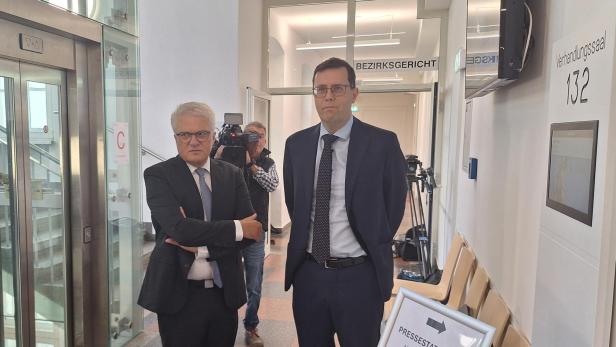 Zwei Männer in Anzügen vor einem Gerichtssaal