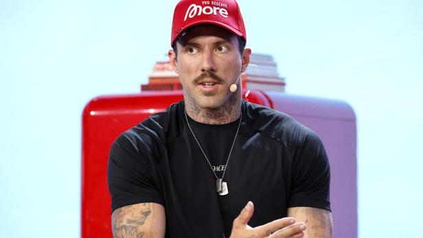Der Unternehmer Christian Wolf spricht in ein Mikrofon, trägt rote Kappe und schwarzes Kurzarmshirt