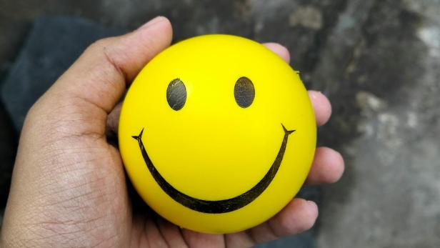Gelber Smiley-Ball in einer Hand