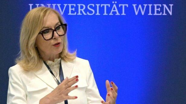 Eine Frau in weißem Blazer spricht an einem Stehpult vor dem Schriftzug „Medizinische Universität Wien“.