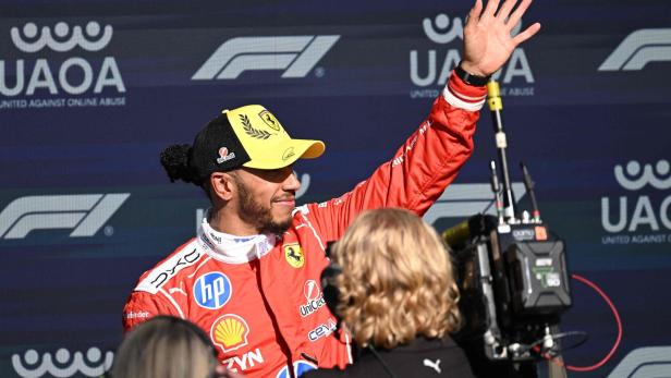 Lewis Hamilton jubelt. Er hat eine schwarz-gelbe Kappe auf. 