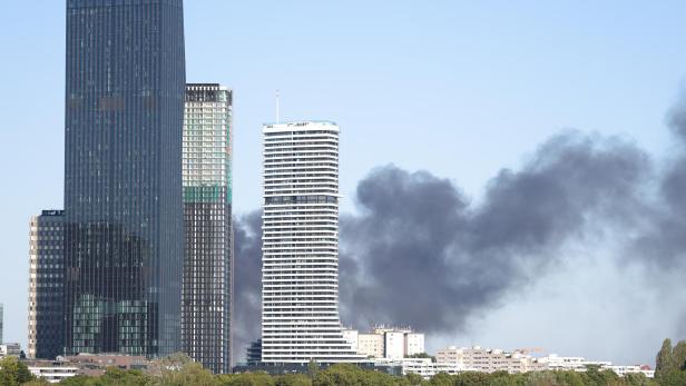 Dunkle Rauchwolken steigen hinter den Hochhäusern der Wiener Donau City auf.
