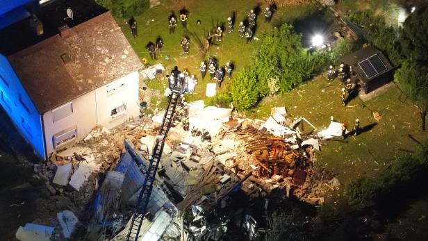 Zerstörtes Wohnhaus nach Gasexplosion, Einsatzkräfte zwischen Trümmern.