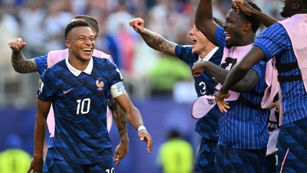 Kylian Mbappé und seine Teamkollegen der französischen Nationalmannschaft jubeln ausgelassen nach einem Torerfolg auf dem Spielfeld.