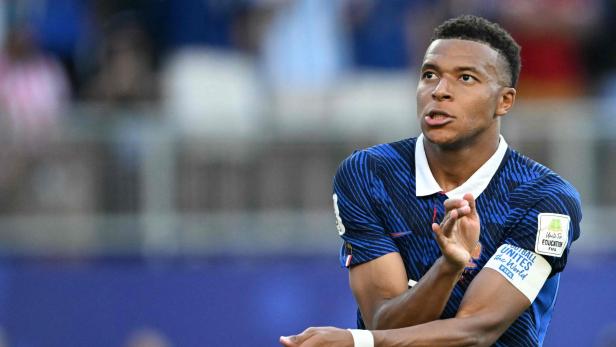 Kylian Mbappé klatscht in die Hände, während er das blaue Trikot der französischen Nationalmannschaft trägt.