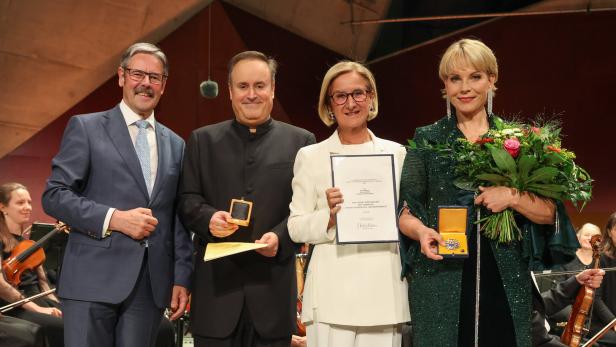 Vier Personen bei einer Preisverleihung, zwei mit Medaille und Urkunde, die Frau rechts hält einen Blumenstrauß.