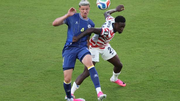 Zwei Fußballer kämpfen um den Ball auf dem Spielfeld.