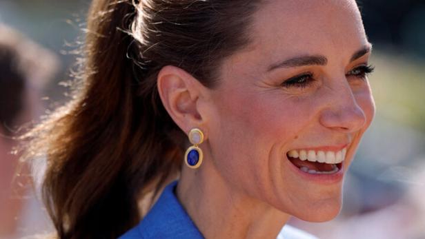 Prinzessin Kate lächelt in einem blauen Blazer mit passenden Ohrringen.