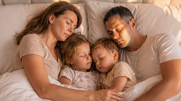 Eine Familie schläft eng aneinander gekuschelt im Bett.