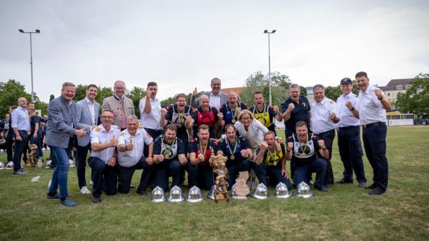 Mehrere Personen stehen gemeinsam auf einer Wiese und freuen sich über den Sieg der Freiwilligen Feuerwehr in Trattenbach bei den Landesfeuerwehrbewerben