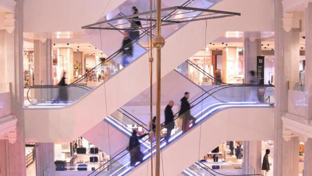 Menschen fahren auf mehreren Rolltreppen in einem Einkaufszentrum.