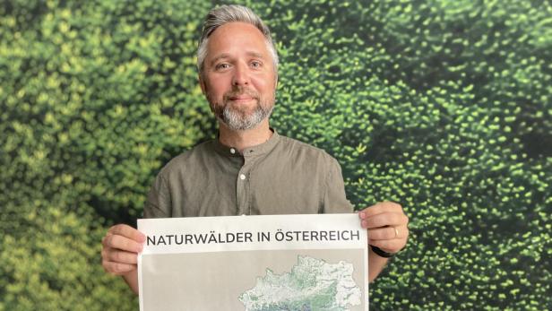 Ein Mann hält eine Österreichkarte in den Händen.