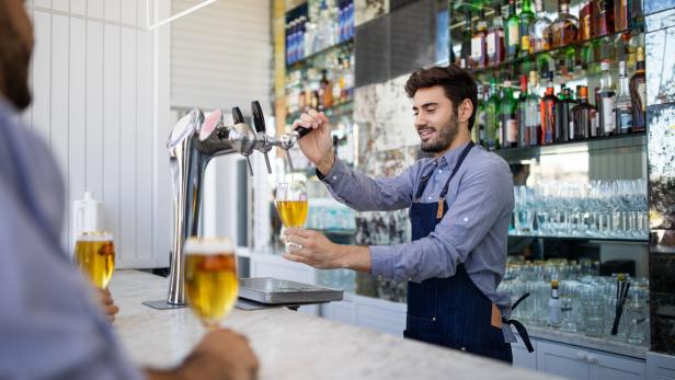 Bartender filing beer in a glass from tap