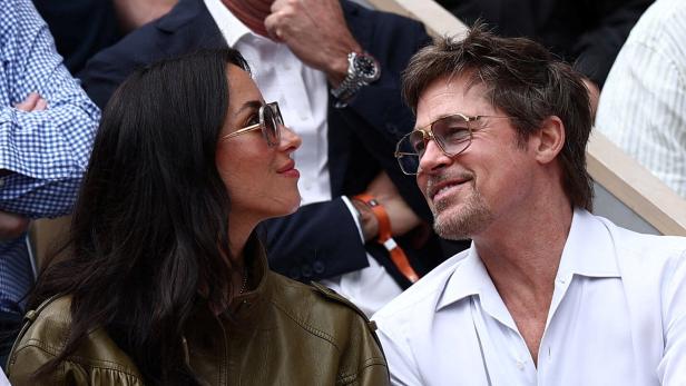 Brad Pitt und Ines de Ramon sitzen nebeneinander und schauen sich lächelnd an.