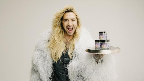 Bill Kaulitz hält ein Tablett mit mehreren Dosen seines Nahrungsergänzungsmittels "BillPill".