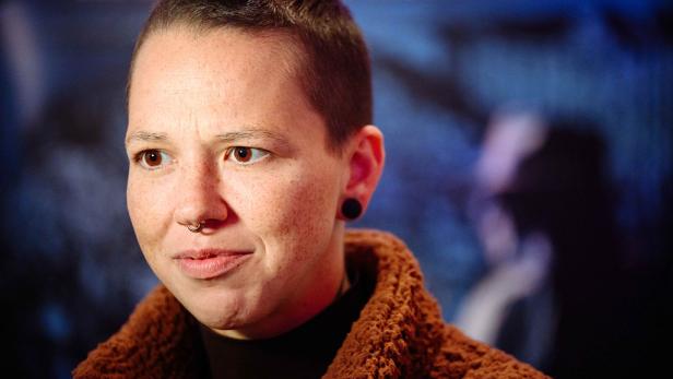 Stefanie Heinzmann mit kurz geschorenen Haaren und Septum-Piercing vor unscharfem Hintergrund.