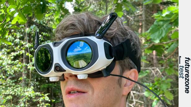 Mann trägt VR-Drohnenbrille im Wald, auf dem Display ist eine Landschaft zu sehen.