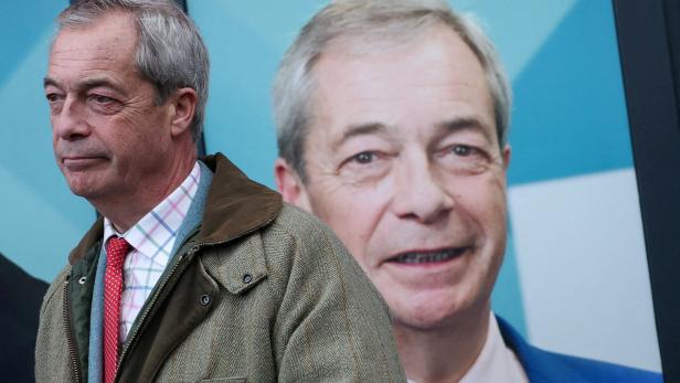 Nigel Farage steht vor einem großen Plakat, das ihn selbst zeigt.