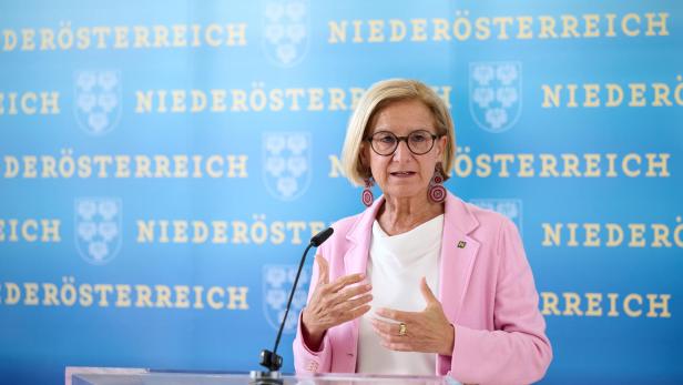Johanna Mikl-Leitner steht vor einem Rednerpult und spricht in ein Mikrofon, hinter ihr ist eine blaue Wand, auf der mit gelben Buchstaben Niederösterreich steht