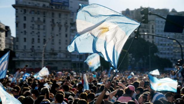 Eine Menschenmenge schwenkt bei einer Feier in Argentinien zahlreiche Nationalflaggen.