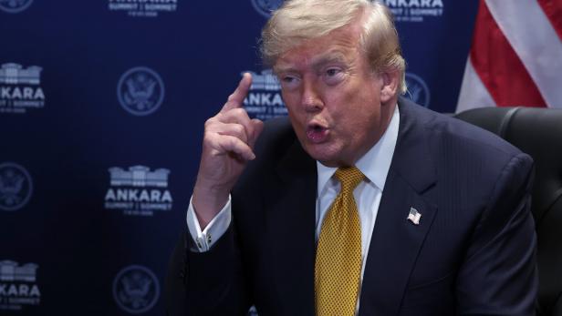 Donald Trump spricht vor einem blauen Hintergrund mit dem Logo des Ankara Summit und hebt dabei mahnend den Zeigefinger.