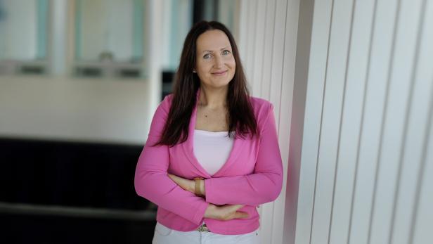 Frau im pinken Blazer mit verschränkten Armen