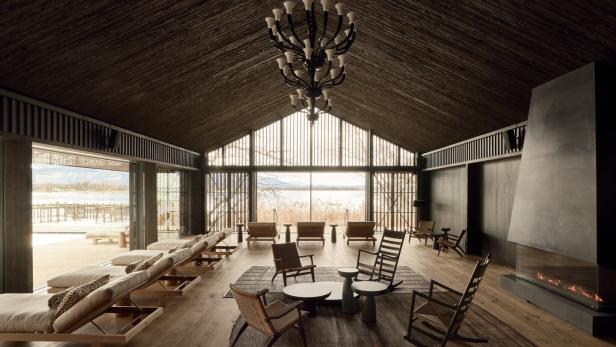 ein hotel mit deckenhohen Fenstern und Sesseln und Tischen aus Holz davor