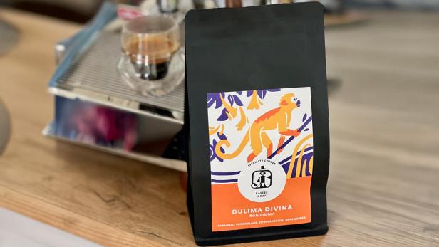Packung mit Kaffeebohnen vor einer Espressomaschine.