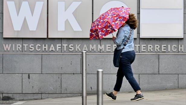 Frau mit Regenschirm vor dem Schild der WKO-Zentrale in Wien