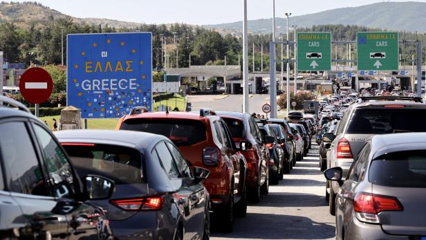 Autoschlange vor dem Grenzübergang nach Griechenland mit Schildern und Stau.
