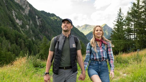 Ein Paar wandert Hand in Hand durch eine alpine Berglandschaft.