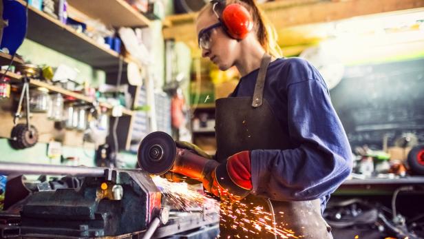 Young woman cutting iron bar in workshop