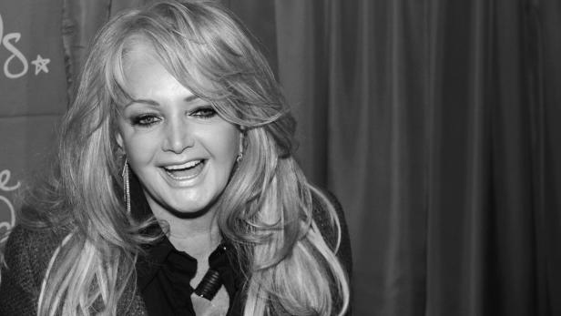 Bonnie Tyler lächelt in die Kamera vor einem dunklen Vorhang.