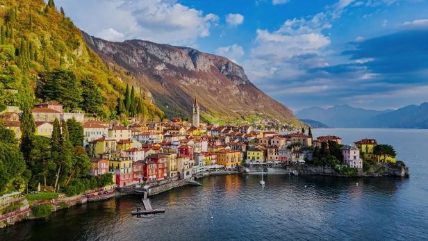 Aerial view of the colorful village of Varenna on the eastern shore of Lake Como with church tower, mountain landscape, and waterfront promenade, Traditional architecture and travel concept in Lombardy, Northern Italy
