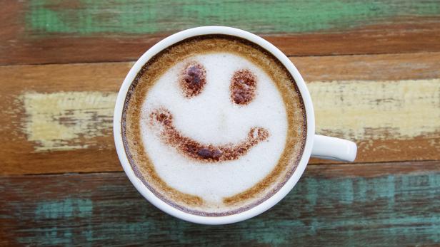 Smile face drawing on latte art coffee , wood color background