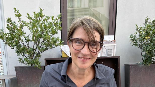 Lisa Totzauer sitzt mit Stäbchen in der Hand und schwarzem Hemd an einem Tisch
