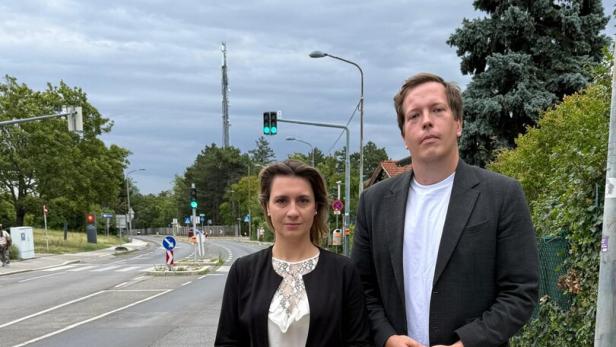 Johanna Zinkl und Patrick Gasselich stehen an einer Straße bei grüner Ampel unter bedecktem Himmel.
